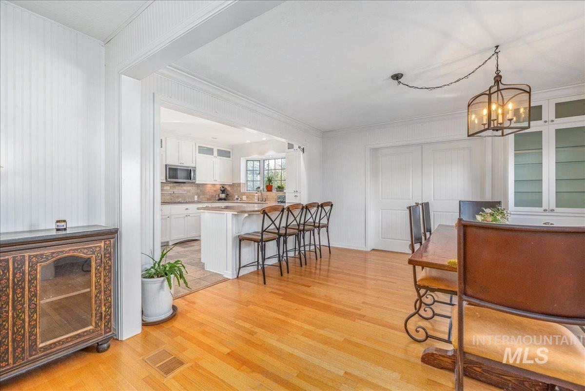Dining area with light wood-style floors, crown molding, and a chandelier