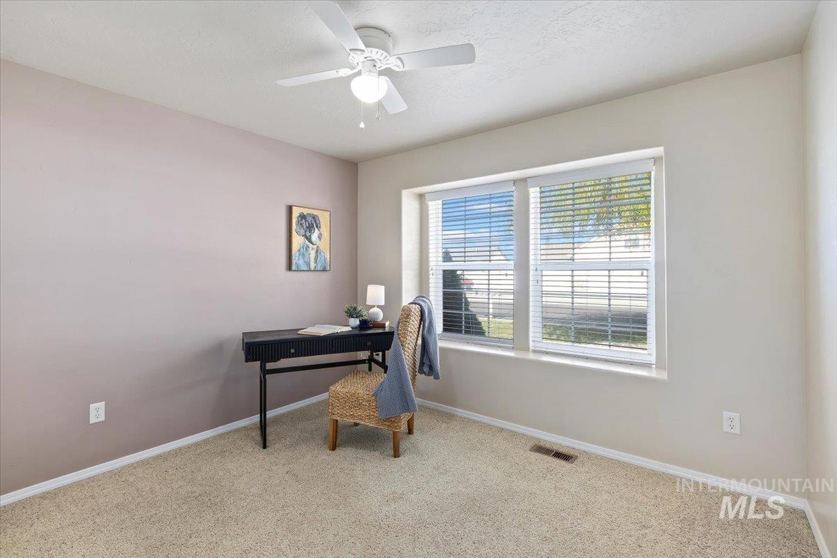 Carpeted office with a ceiling fan and a textured ceiling
