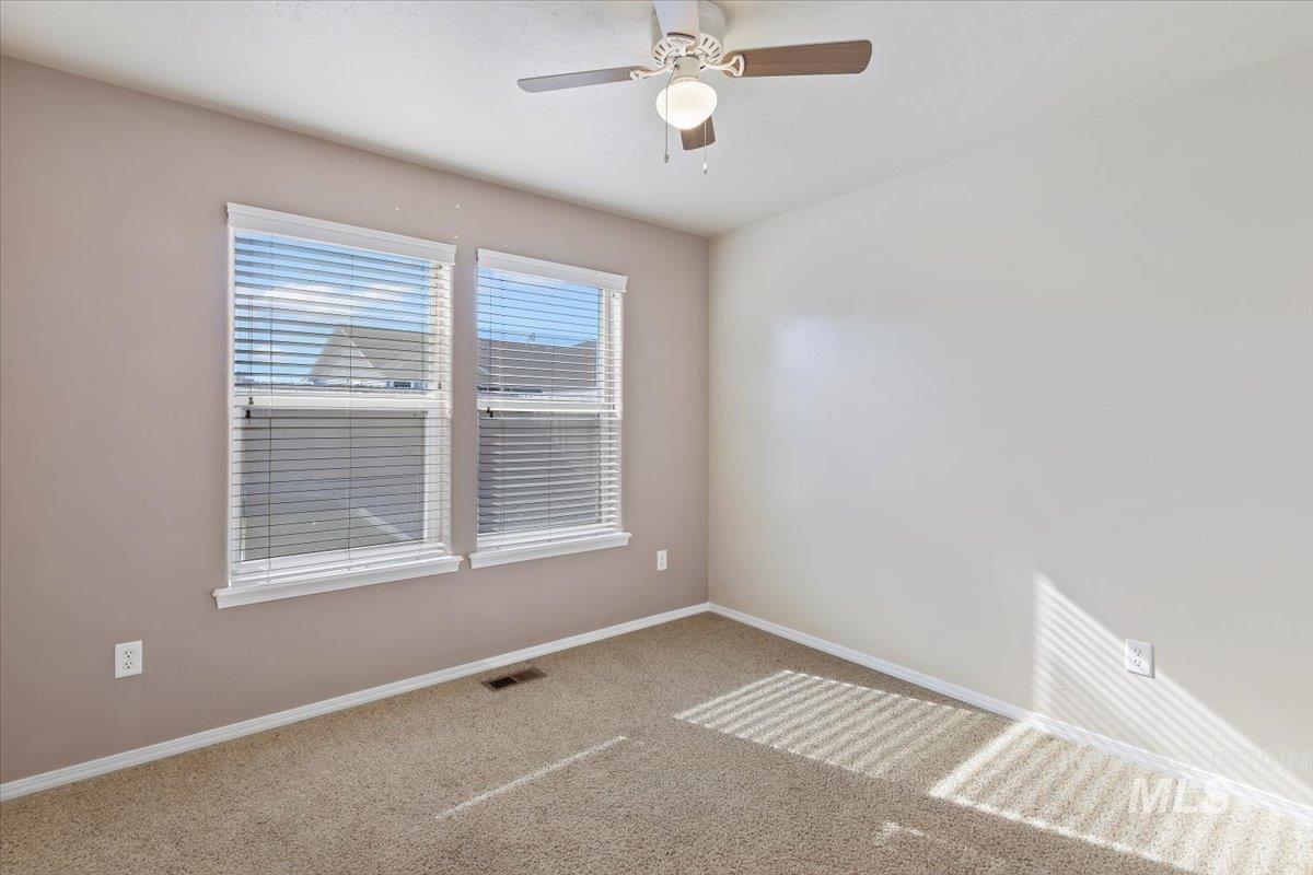 Carpeted empty room with baseboards and a ceiling fan
