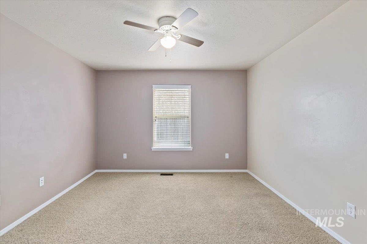 Unfurnished room featuring carpet floors, a textured ceiling, and a ceiling fan