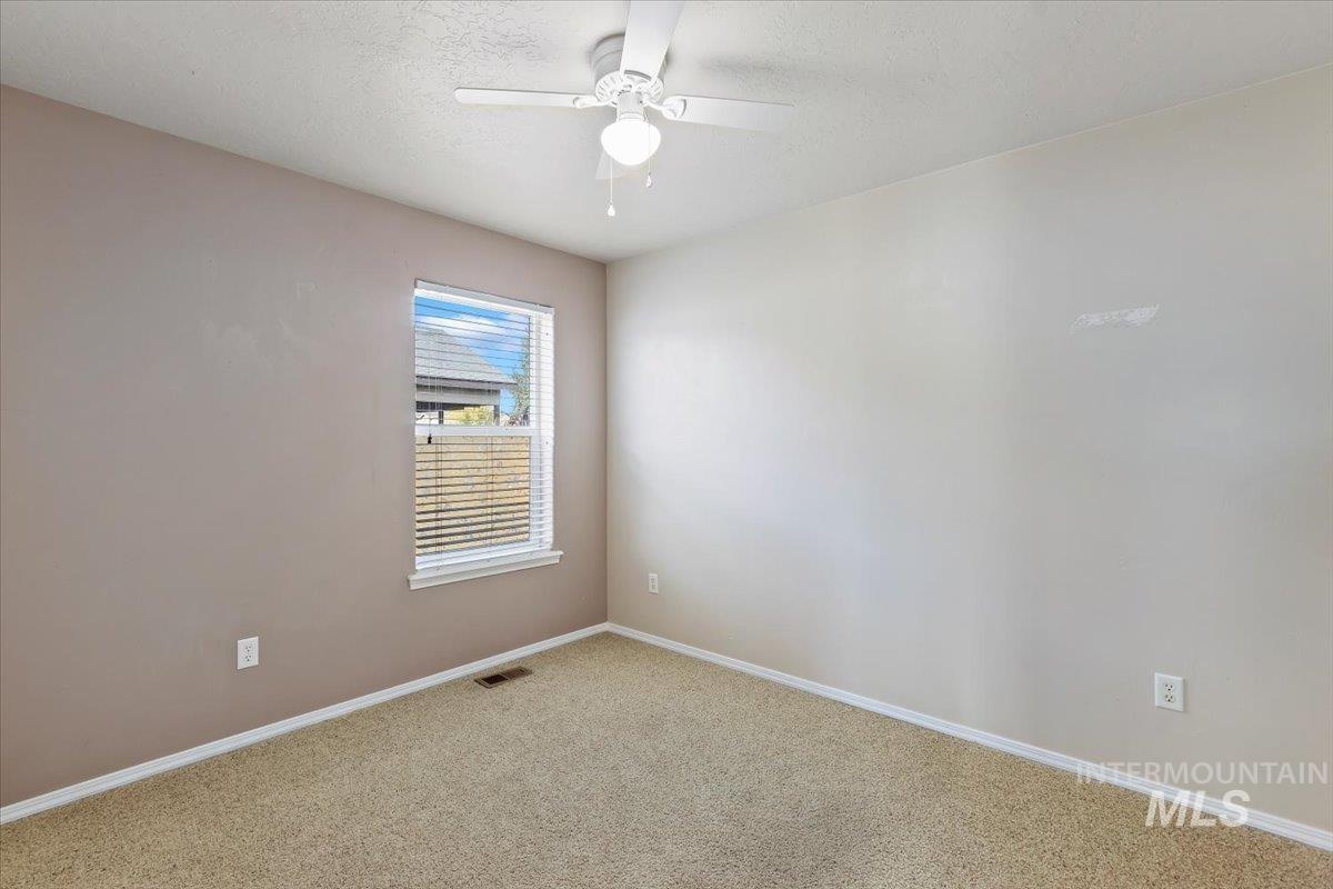 Carpeted empty room with a textured ceiling and ceiling fan