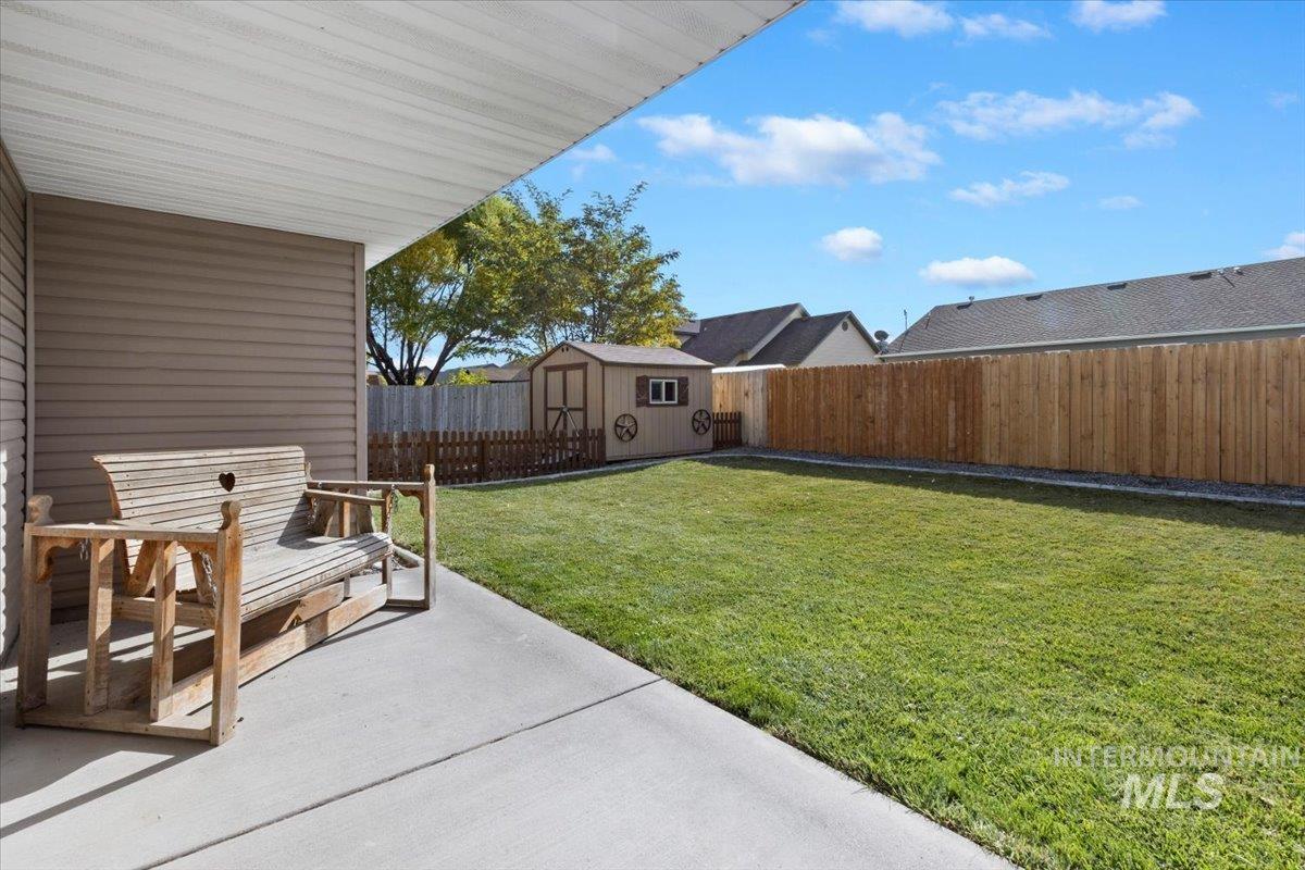 Fenced backyard featuring a storage unit and a patio area