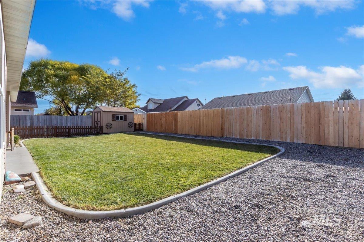 Fenced backyard featuring a shed