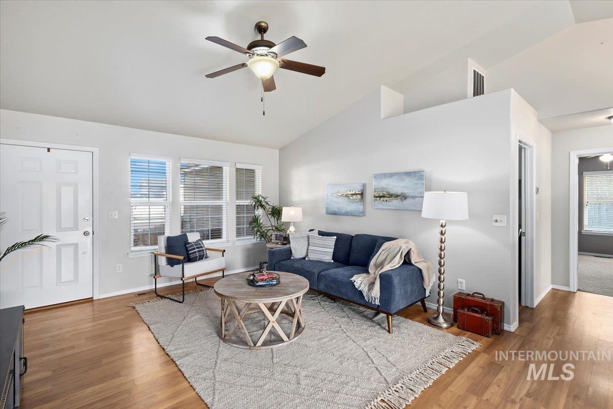 Living area with light wood-type flooring, ceiling fan, and high vaulted ceiling