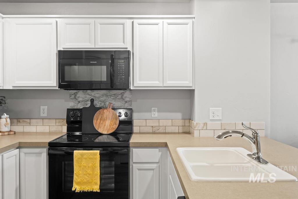 Kitchen with black appliances, white cabinets, and light countertops