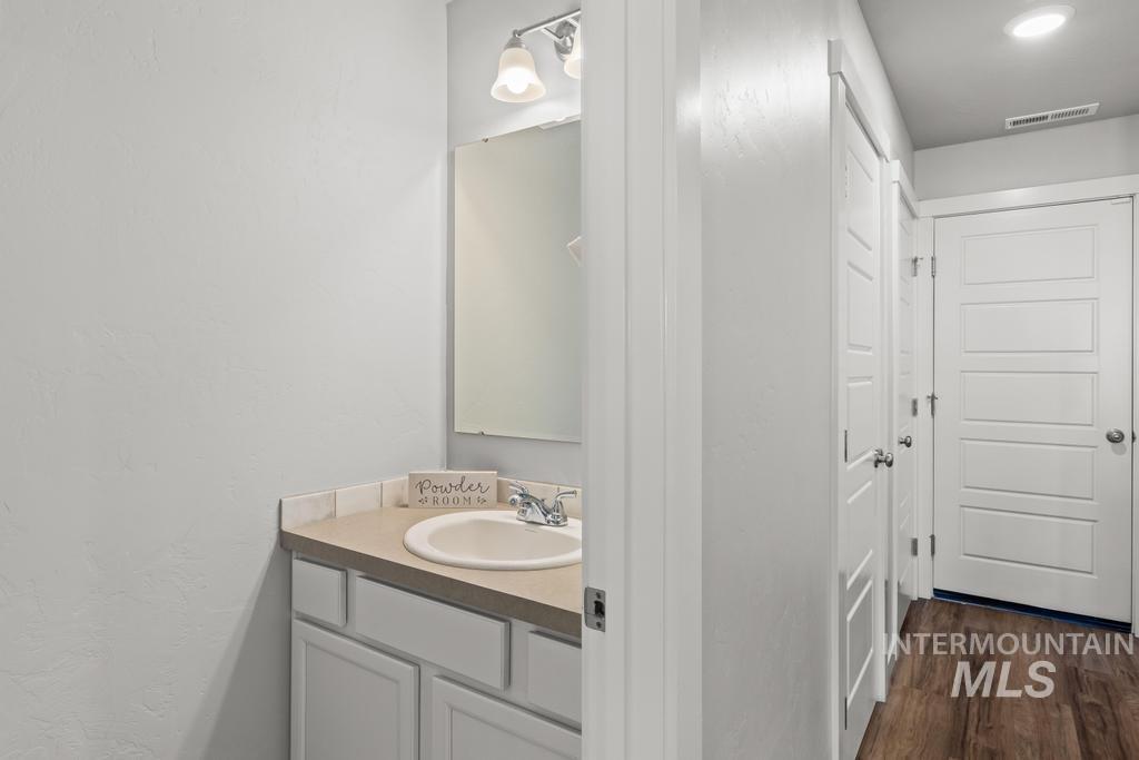 Half bathroom featuring vanity and dark wood finished floors