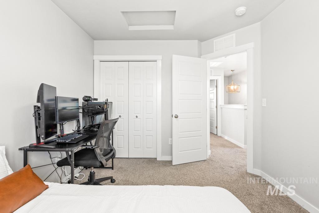 Bedroom with light colored carpet, a closet, a desk, and attic access
