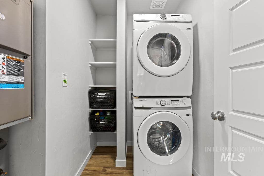 Washroom featuring dark wood finished floors and stacked washer / dryer
