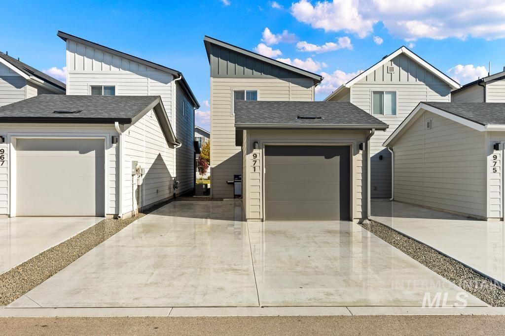 View of front of house with board and batten siding, roof with shingles, driveway, and a garage
