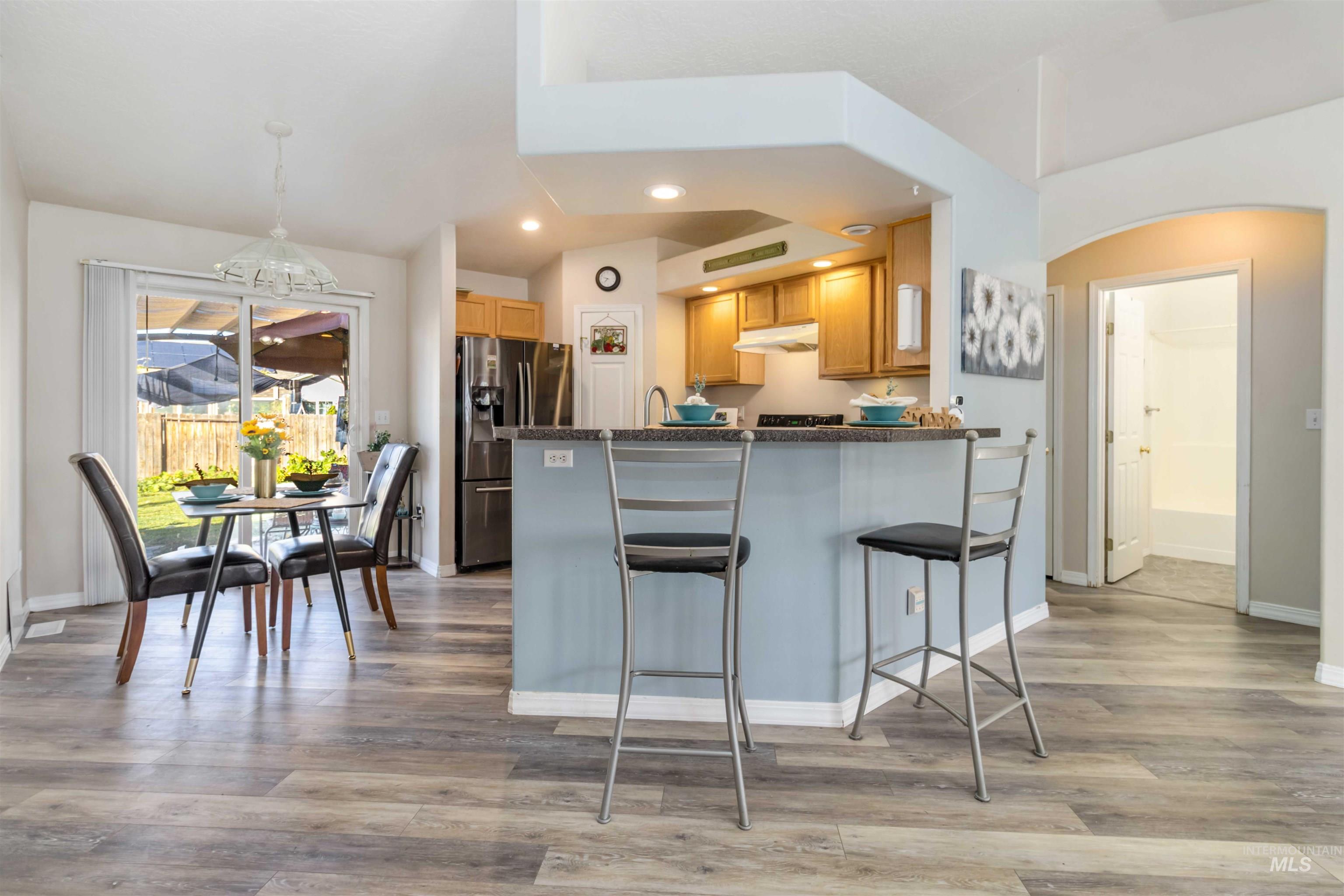 Kitchen with arched walkways, recessed lighting, stainless steel refrigerator with ice dispenser, a kitchen bar, and light wood finished floors