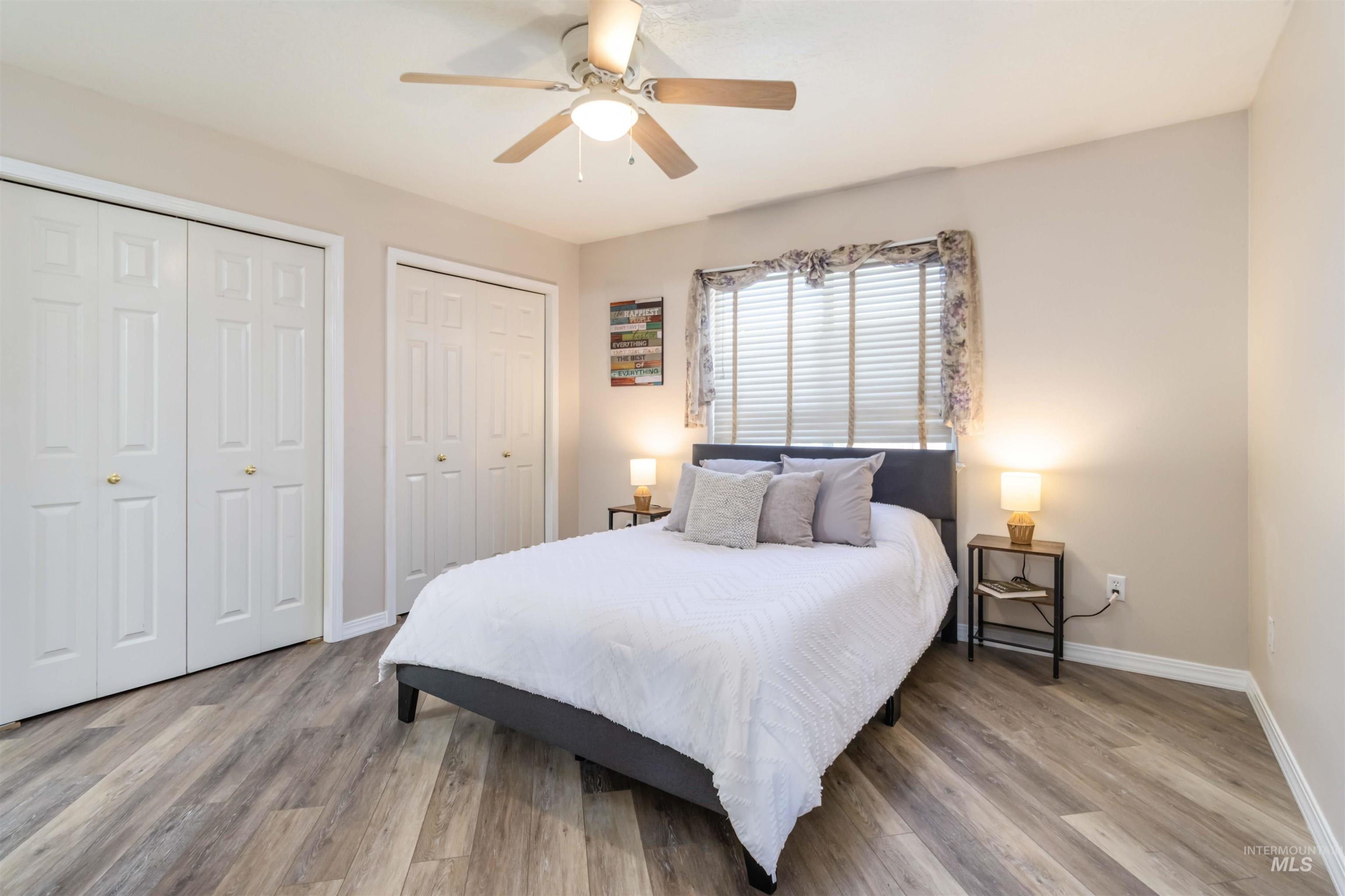 Bedroom with multiple closets, light wood finished floors, and ceiling fan