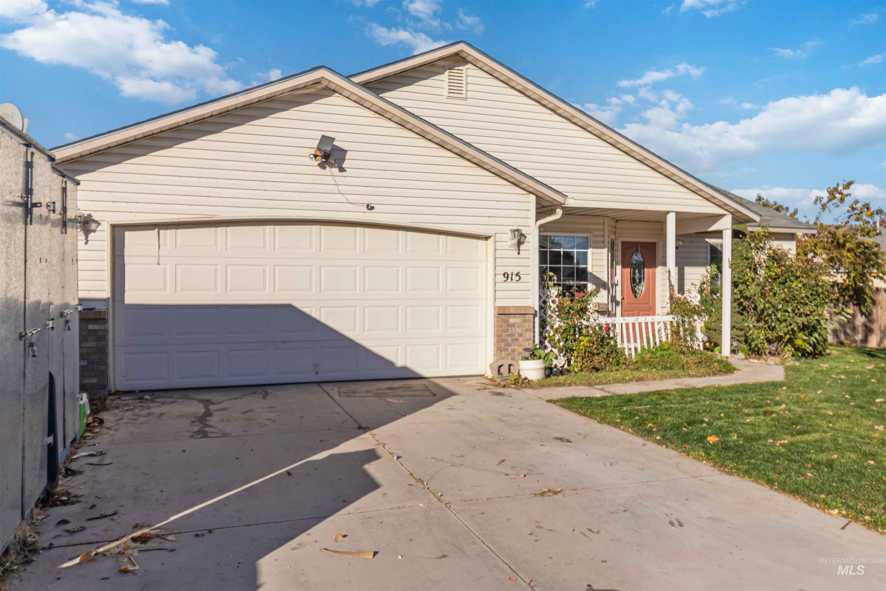 Ranch-style home featuring a porch, driveway, an attached garage, and a front yard