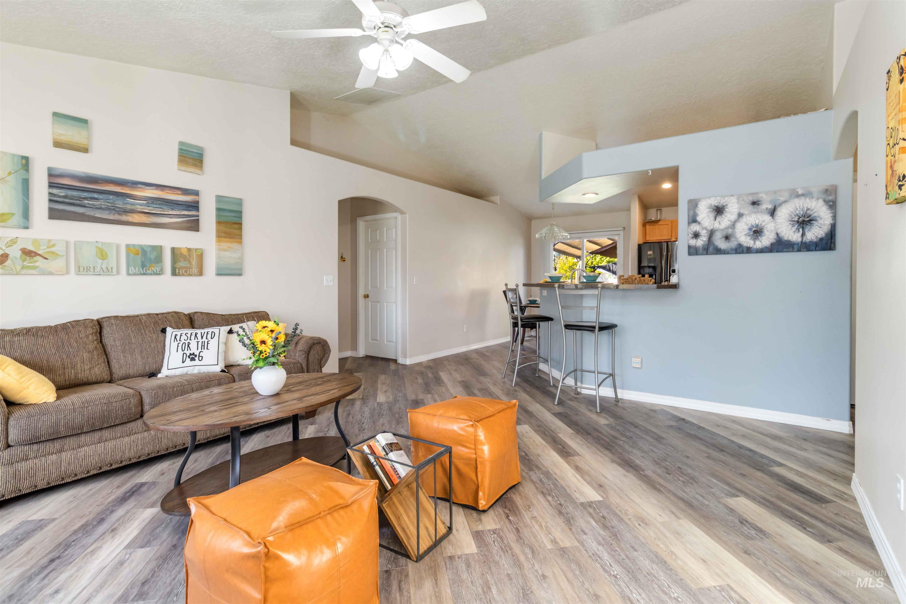 Living room with arched walkways, vaulted ceiling, light wood finished floors, and ceiling fan