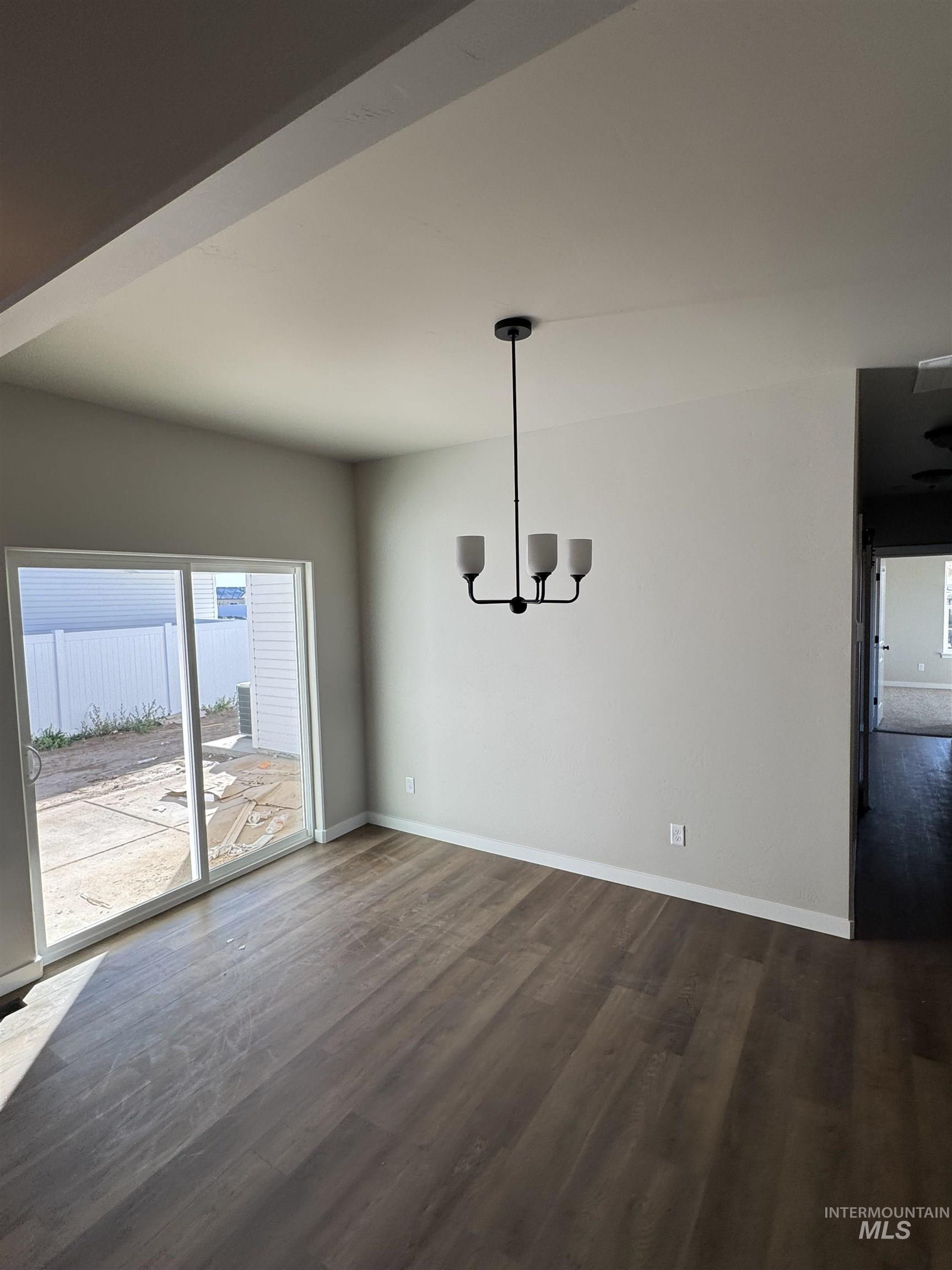 Unfurnished dining area with dark wood-type flooring and a chandelier