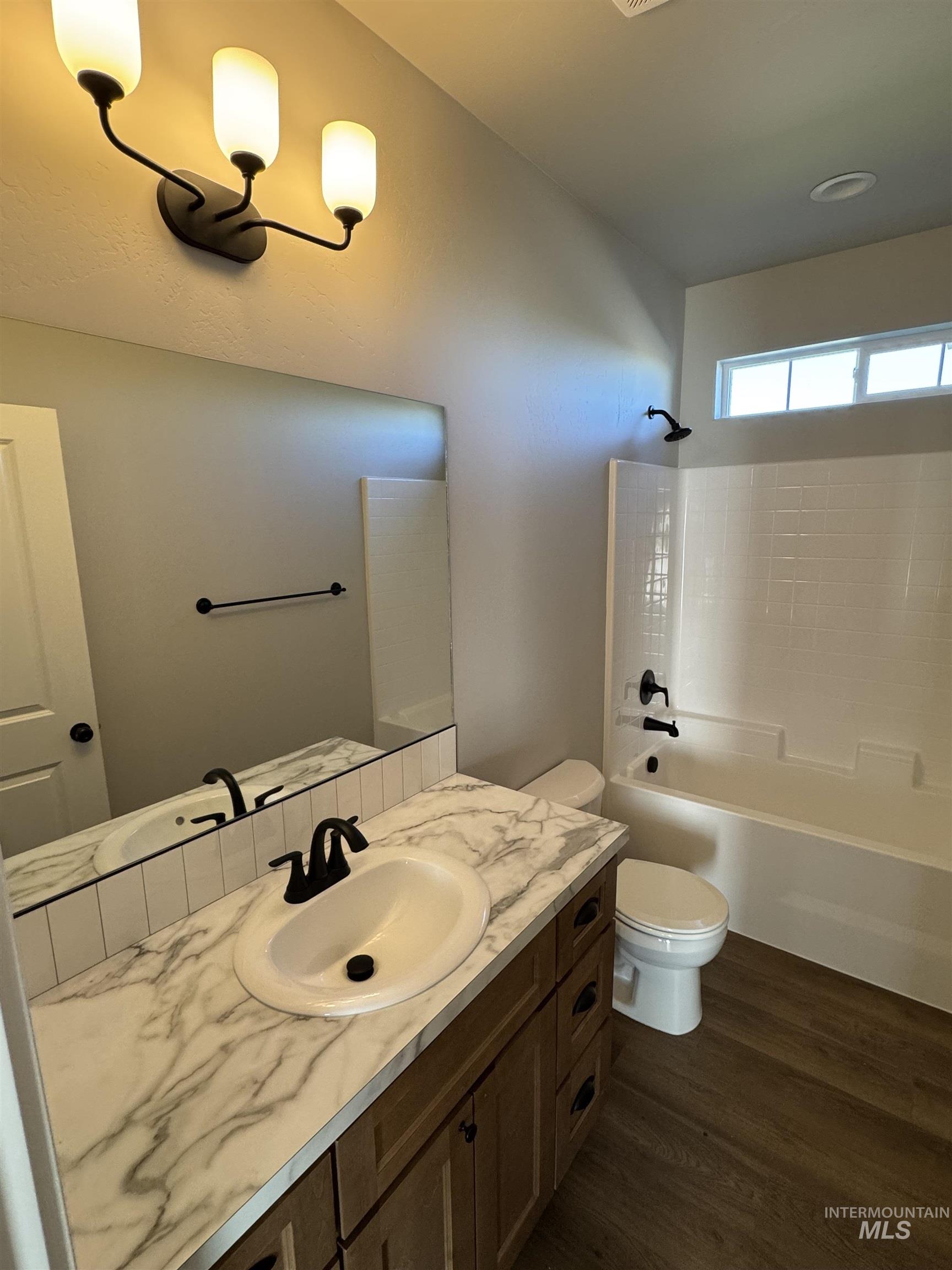 Bathroom featuring dark wood-style floors, vanity, and shower / tub combination