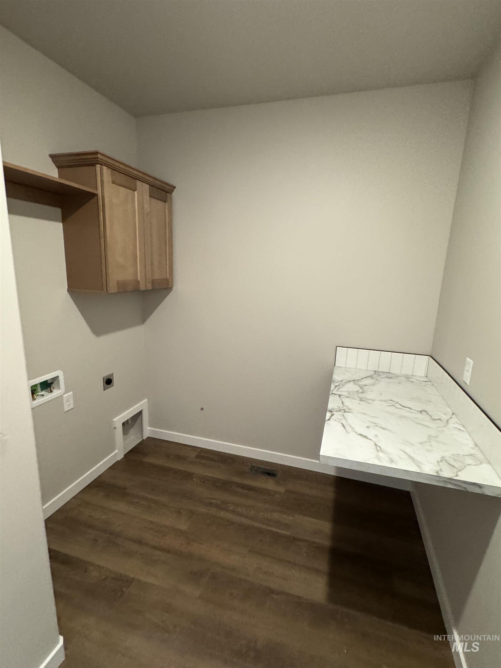 Laundry area with dark wood-style flooring, hookup for an electric dryer, cabinet space, and washer hookup