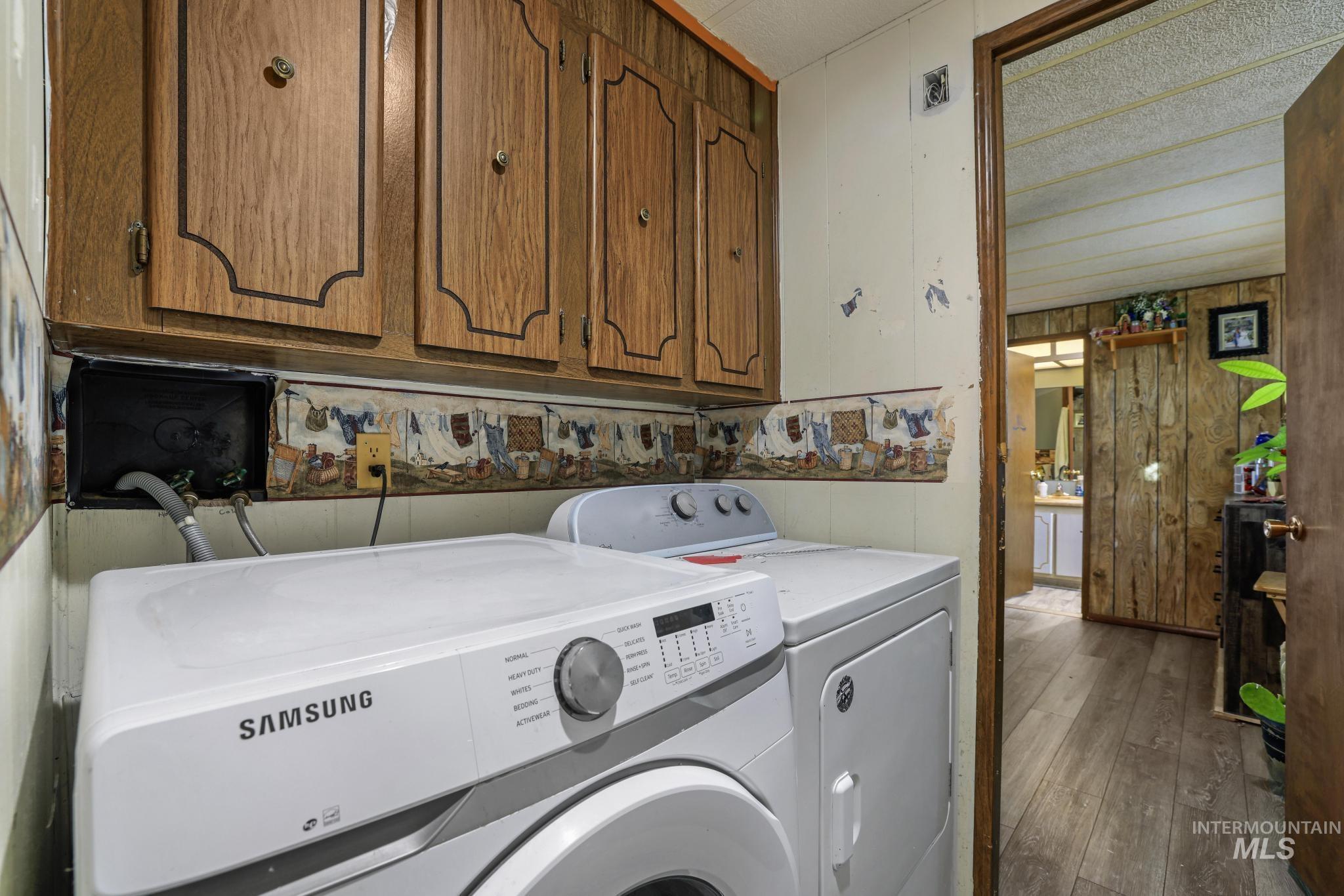 Washroom featuring wooden walls, cabinet space, hardwood / wood-style flooring, and washer and clothes dryer