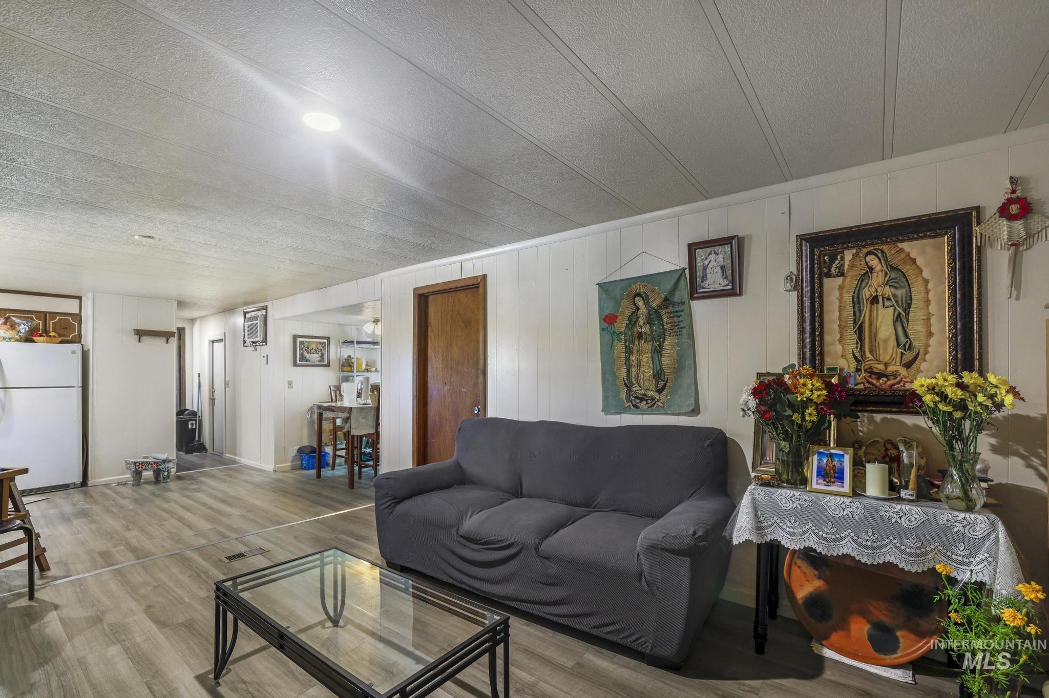 Living area featuring wooden walls, wood finished floors, and a textured ceiling