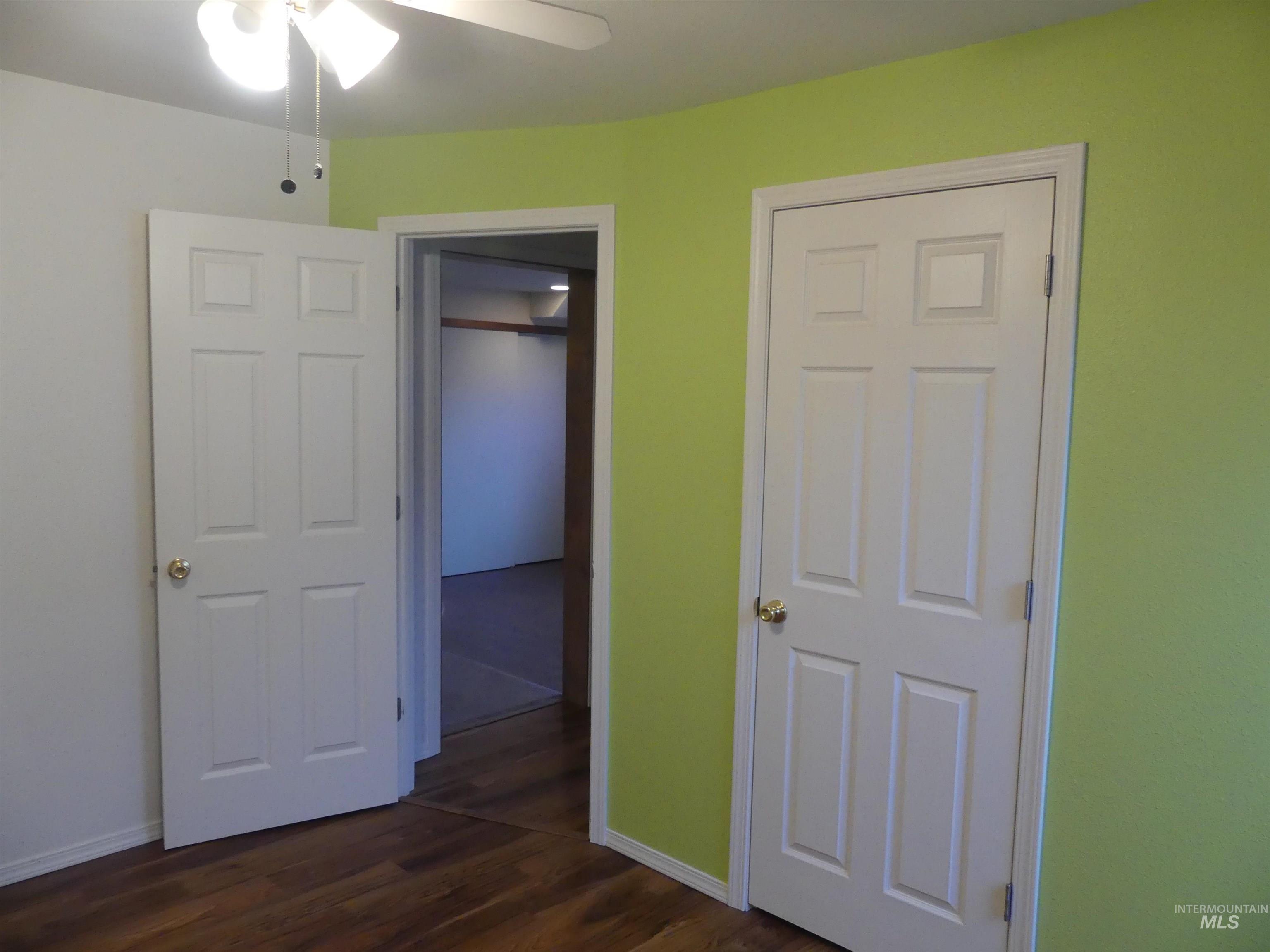 Unfurnished bedroom featuring dark wood-style flooring, ceiling fan, and a closet