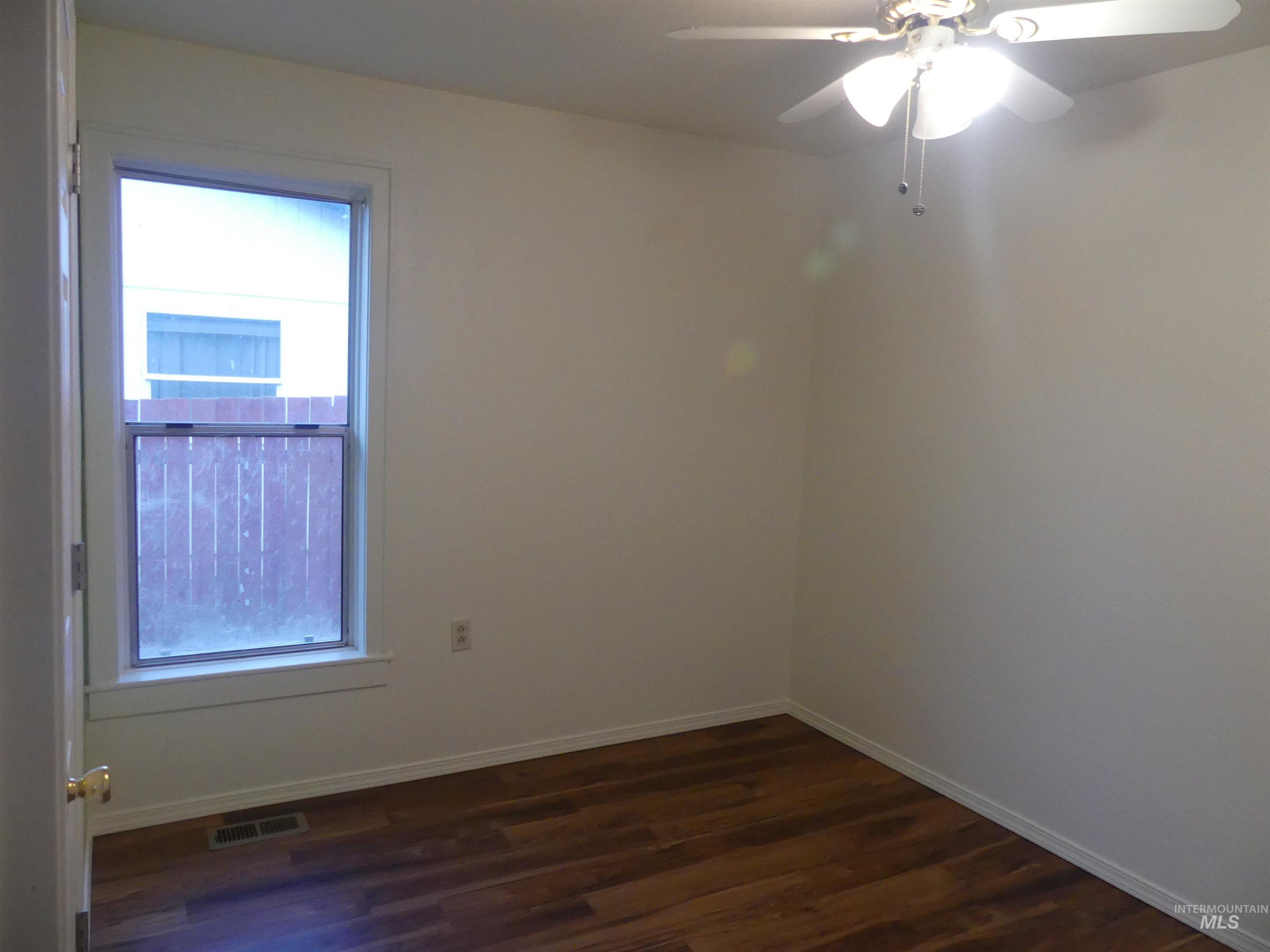 Unfurnished room with ceiling fan and dark wood-style flooring