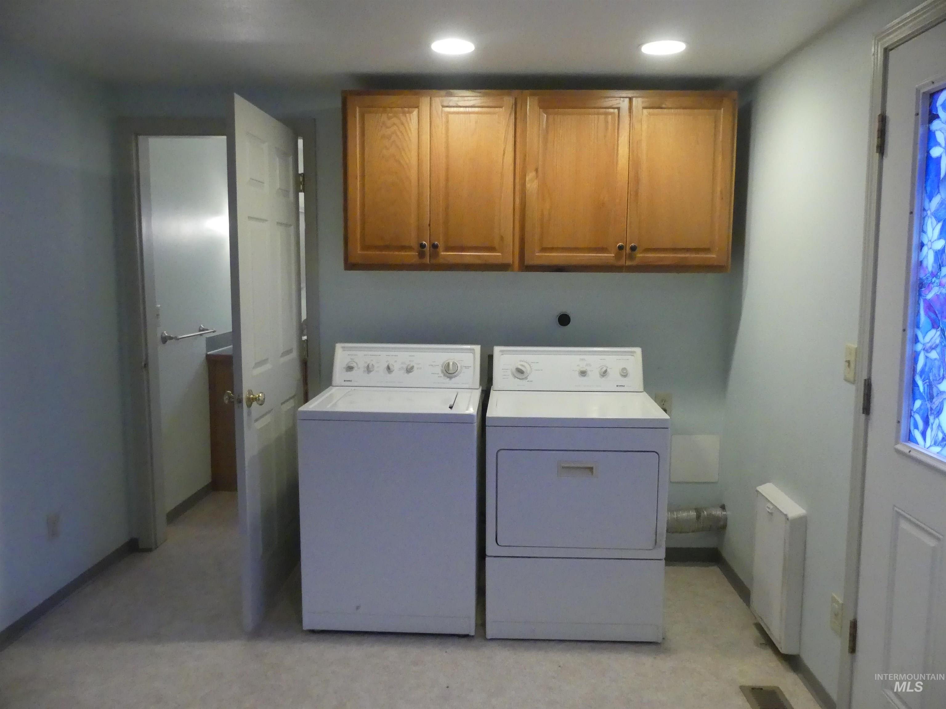 Washroom with independent washer and dryer, cabinet space, light floors, radiator, and recessed lighting