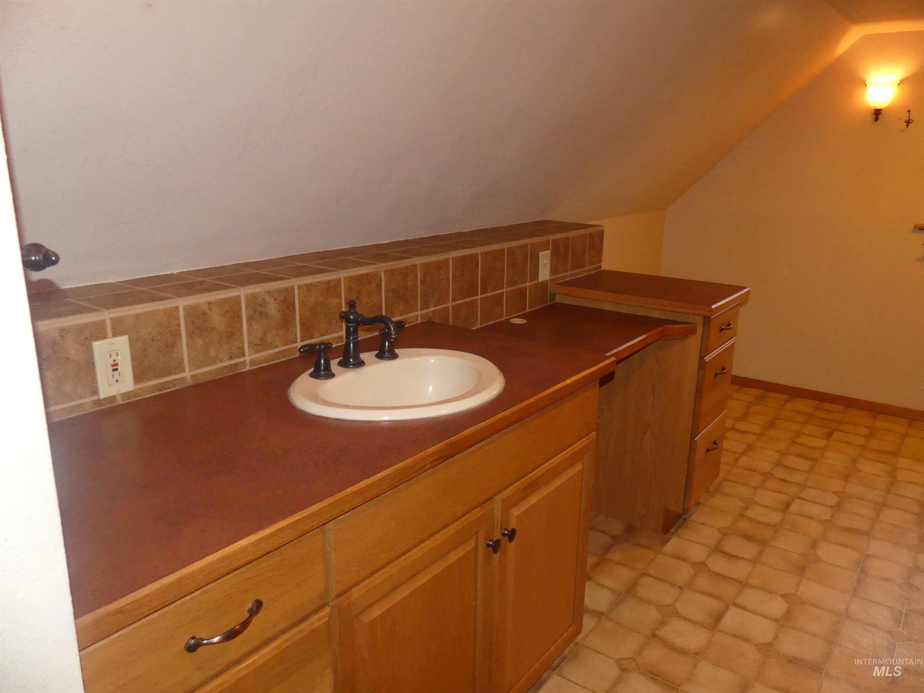 Bathroom with vanity and lofted ceiling