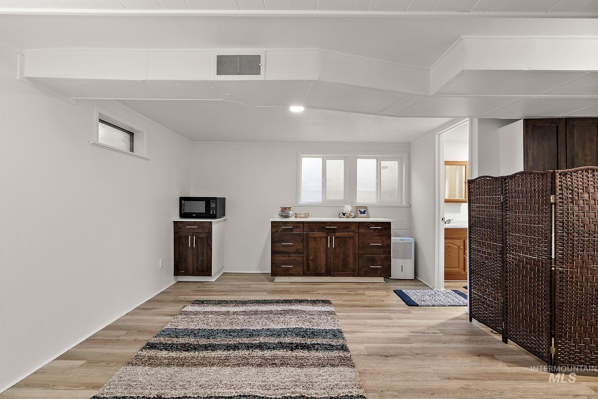 Kitchen with healthy amount of natural light, light wood-style floors, light countertops, and black microwave