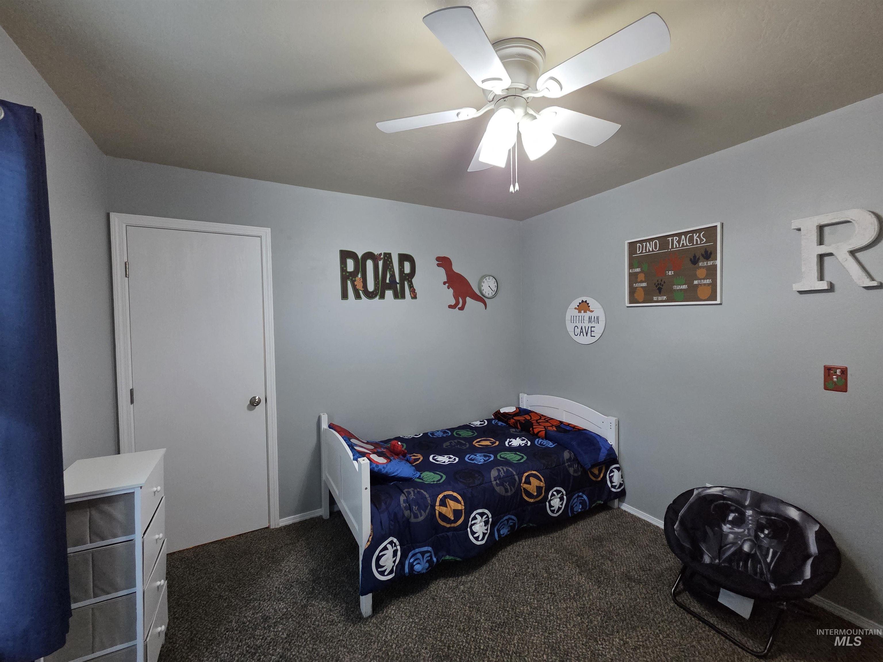 Bedroom with dark carpet and a ceiling fan