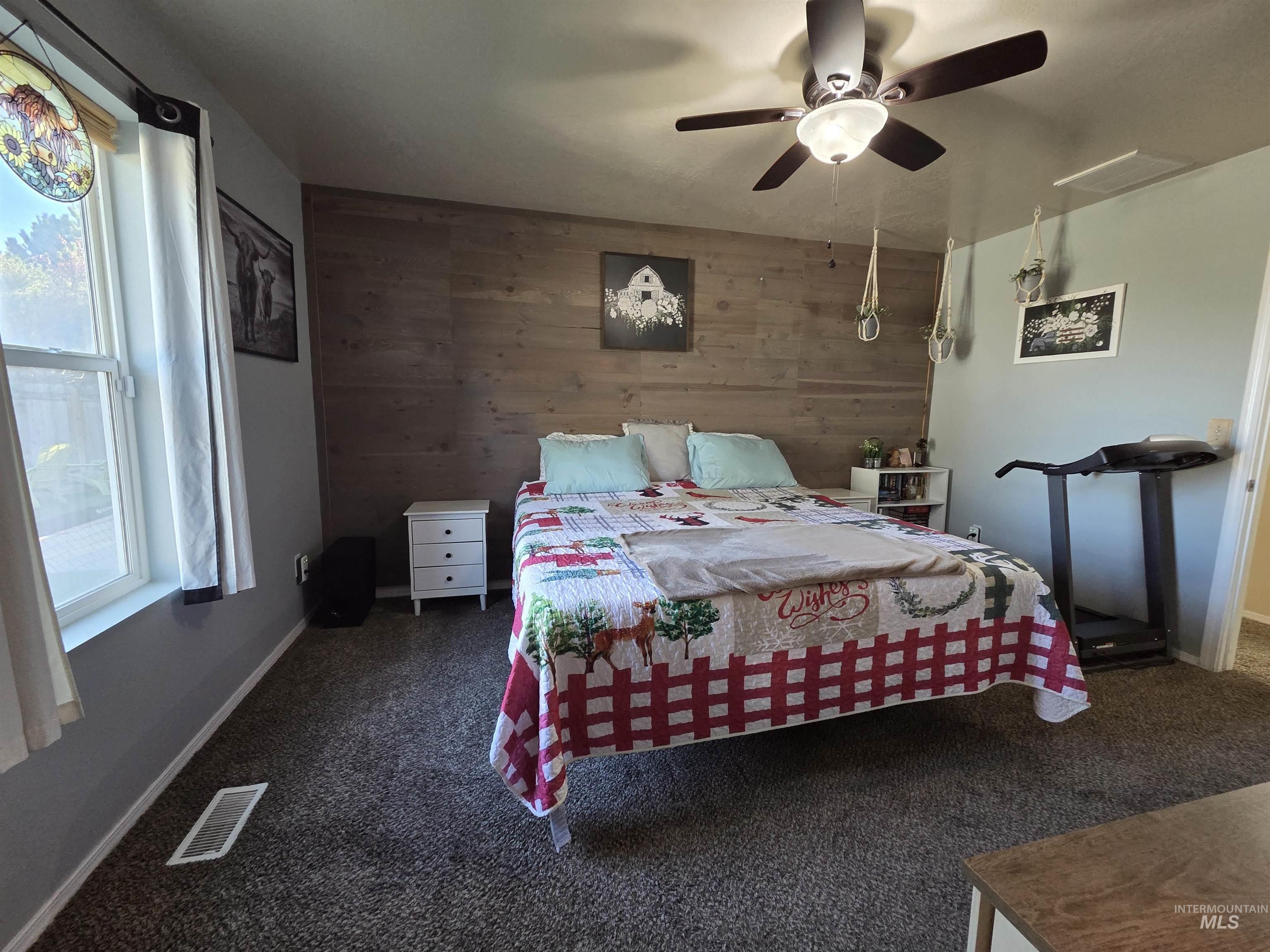 Bedroom with wood walls, carpet, and a ceiling fan