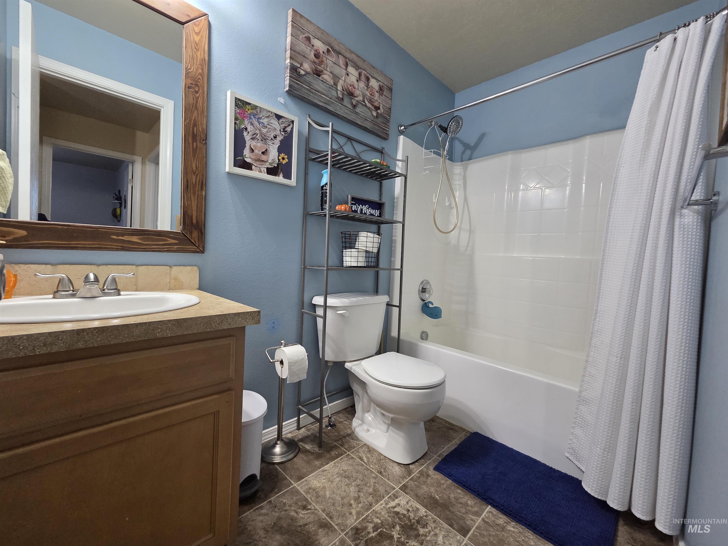 Bathroom with shower / bath combination with curtain, vanity, and dark tile patterned flooring