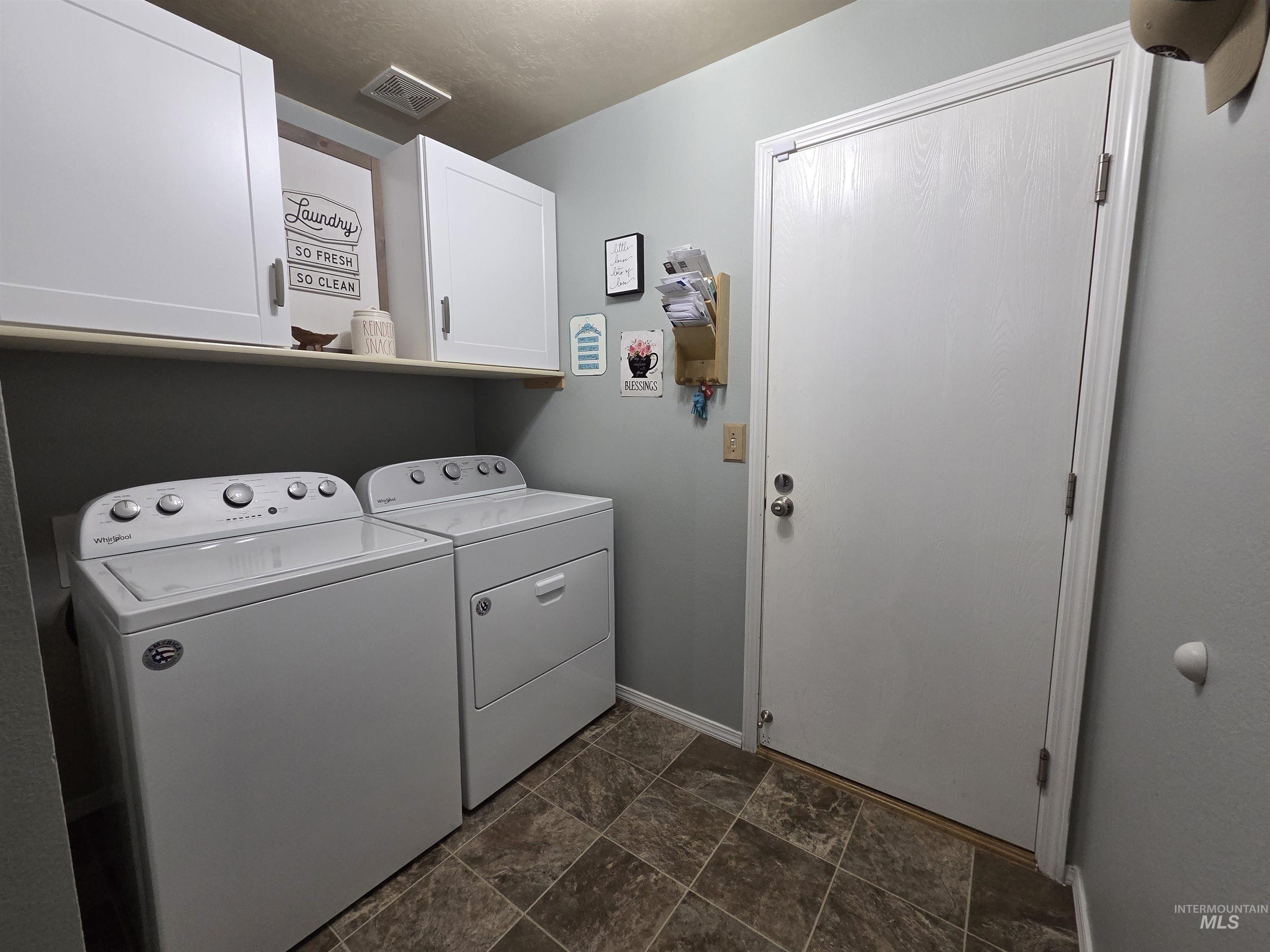 Washroom with separate washer and dryer, stone finish floors, and cabinet space