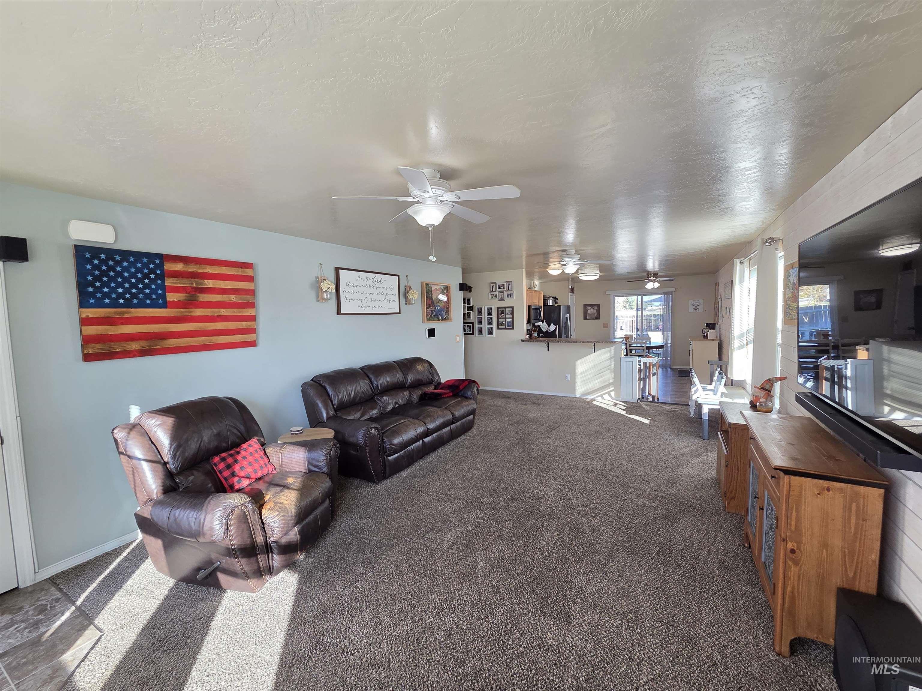 Carpeted living room featuring a textured ceiling and a ceiling fan