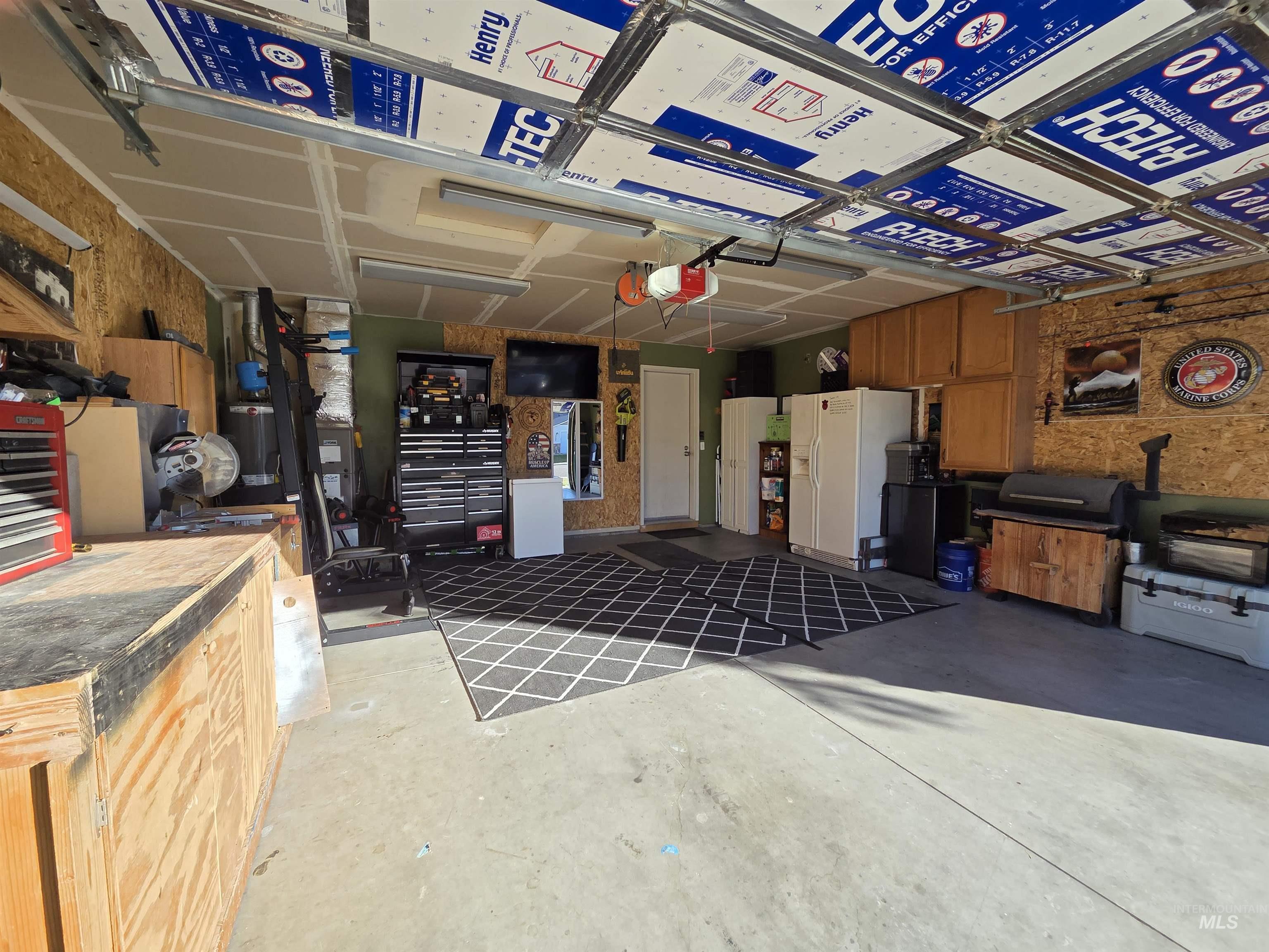Garage featuring white refrigerator with ice dispenser and a garage door opener