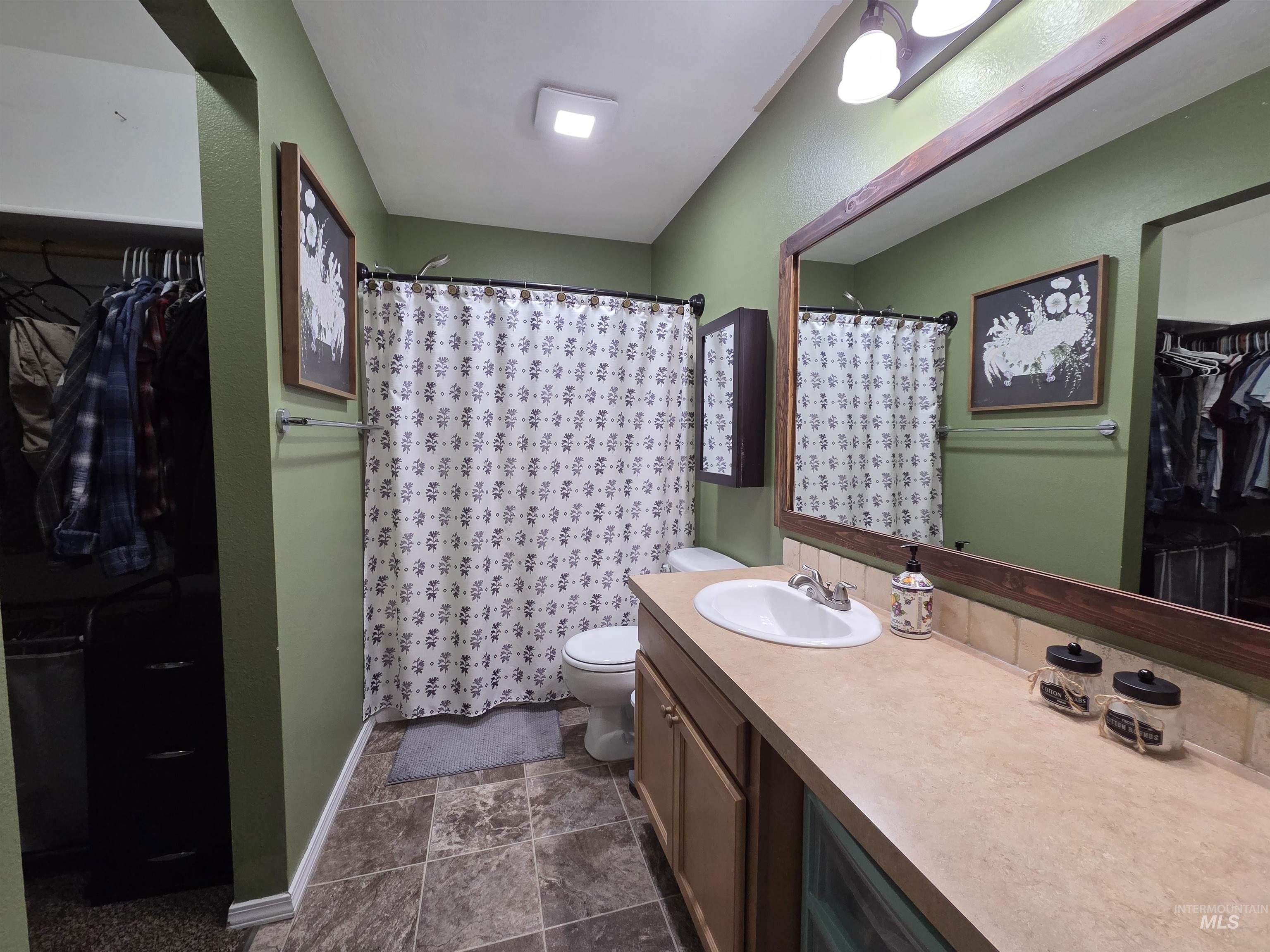 Full bath featuring a spacious closet, a shower stall, and vanity