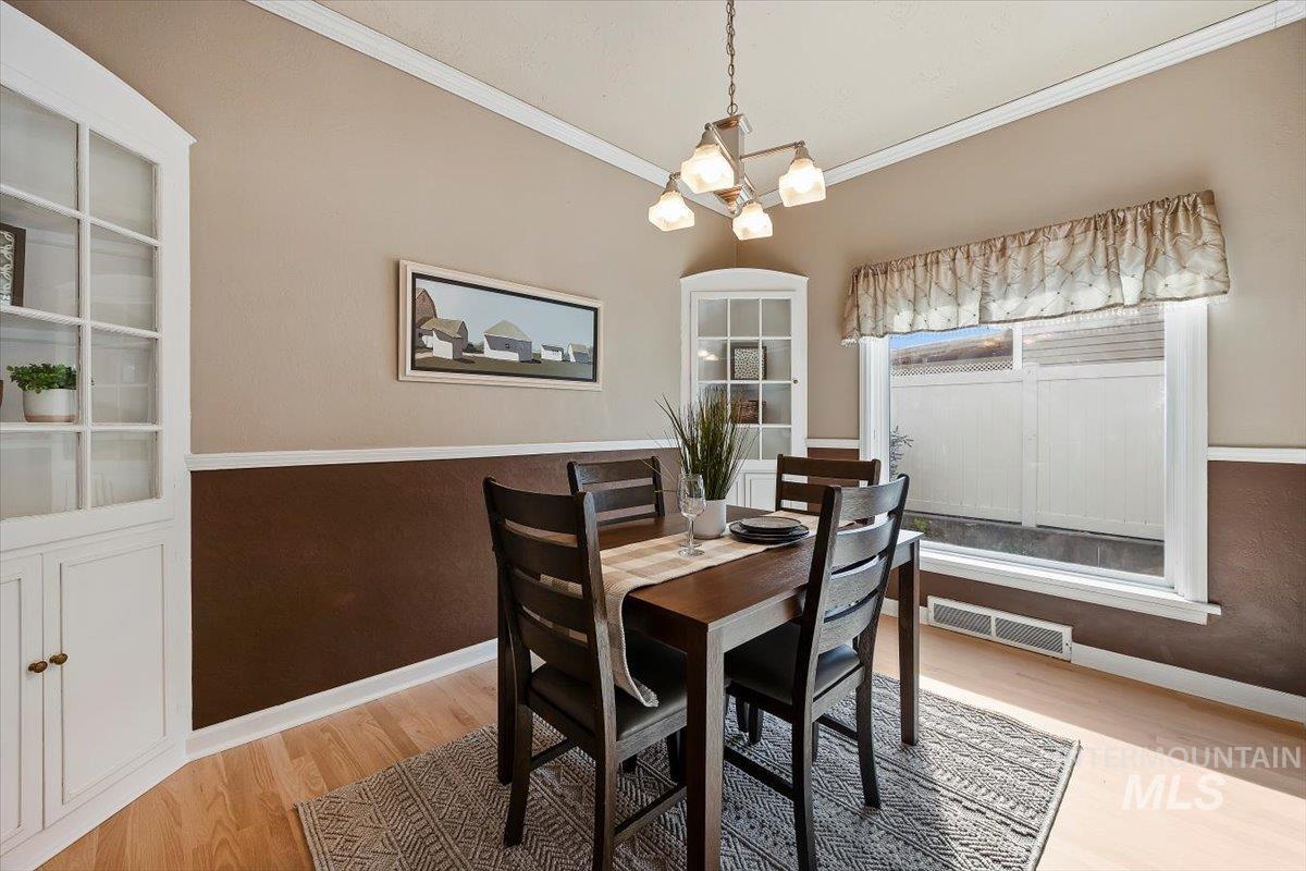 Dining room with light wood-style flooring, crown molding, a chandelier, and built in features