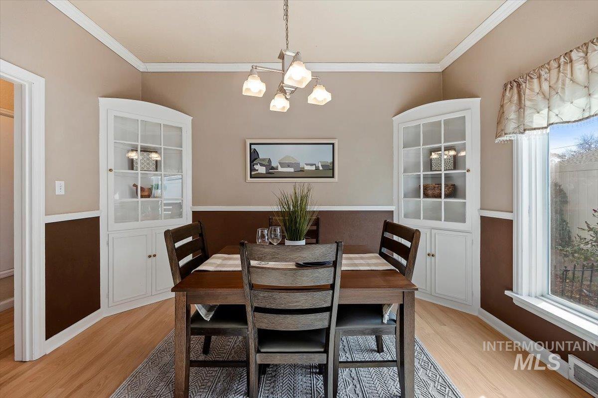 Dining area featuring crown molding, light wood-style flooring, and a chandelier