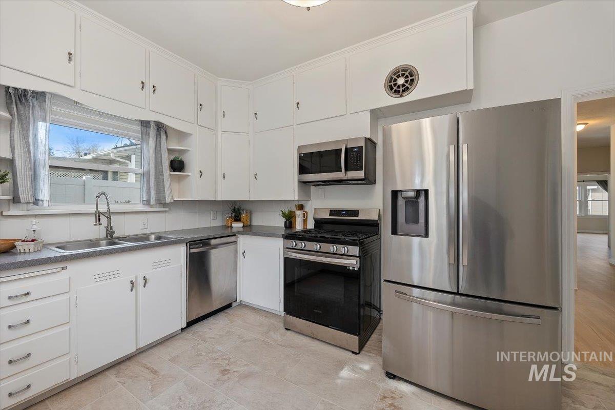 Kitchen with appliances with stainless steel finishes, white cabinets, and dark countertops