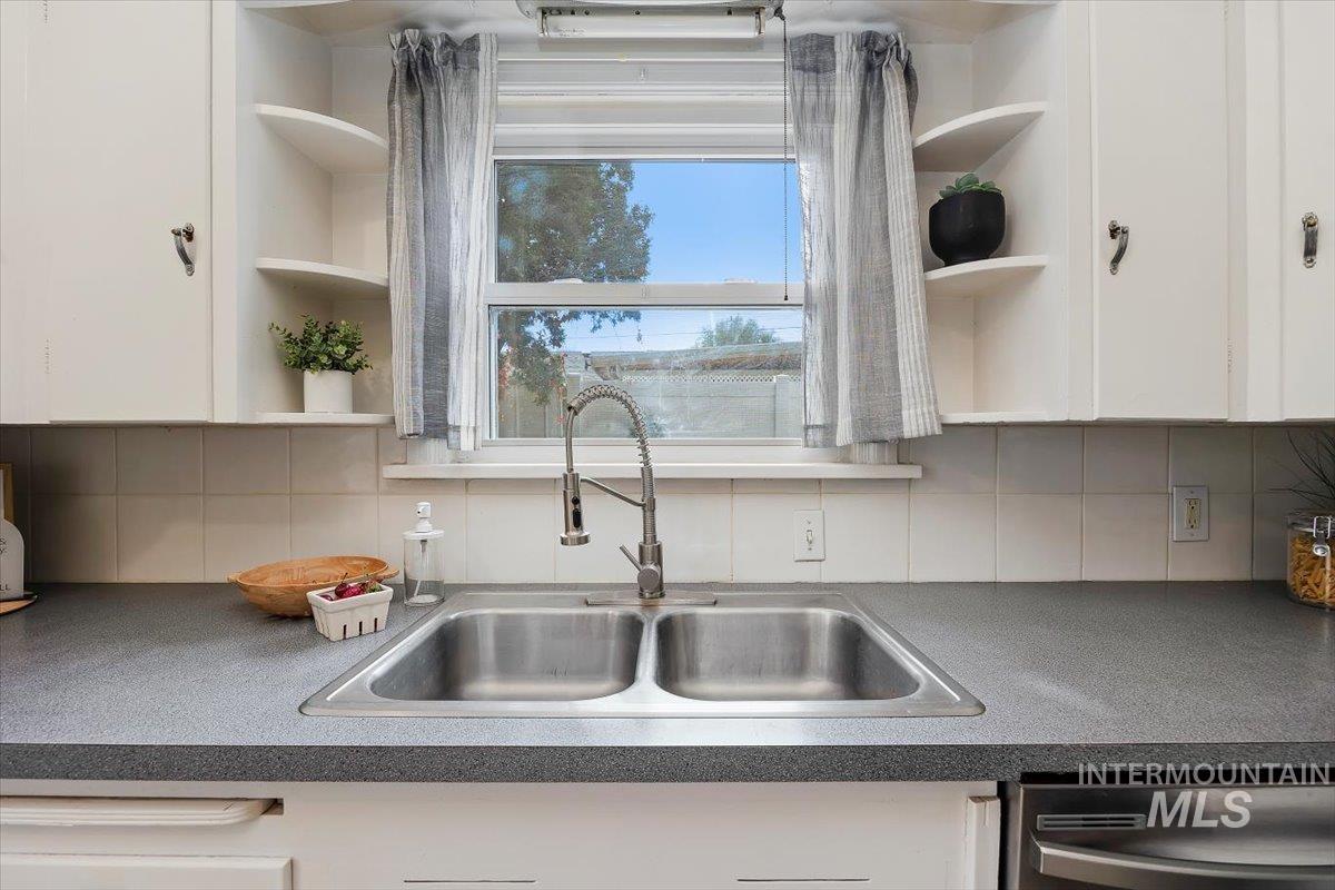 Kitchen with open shelves, backsplash, and white cabinetry
