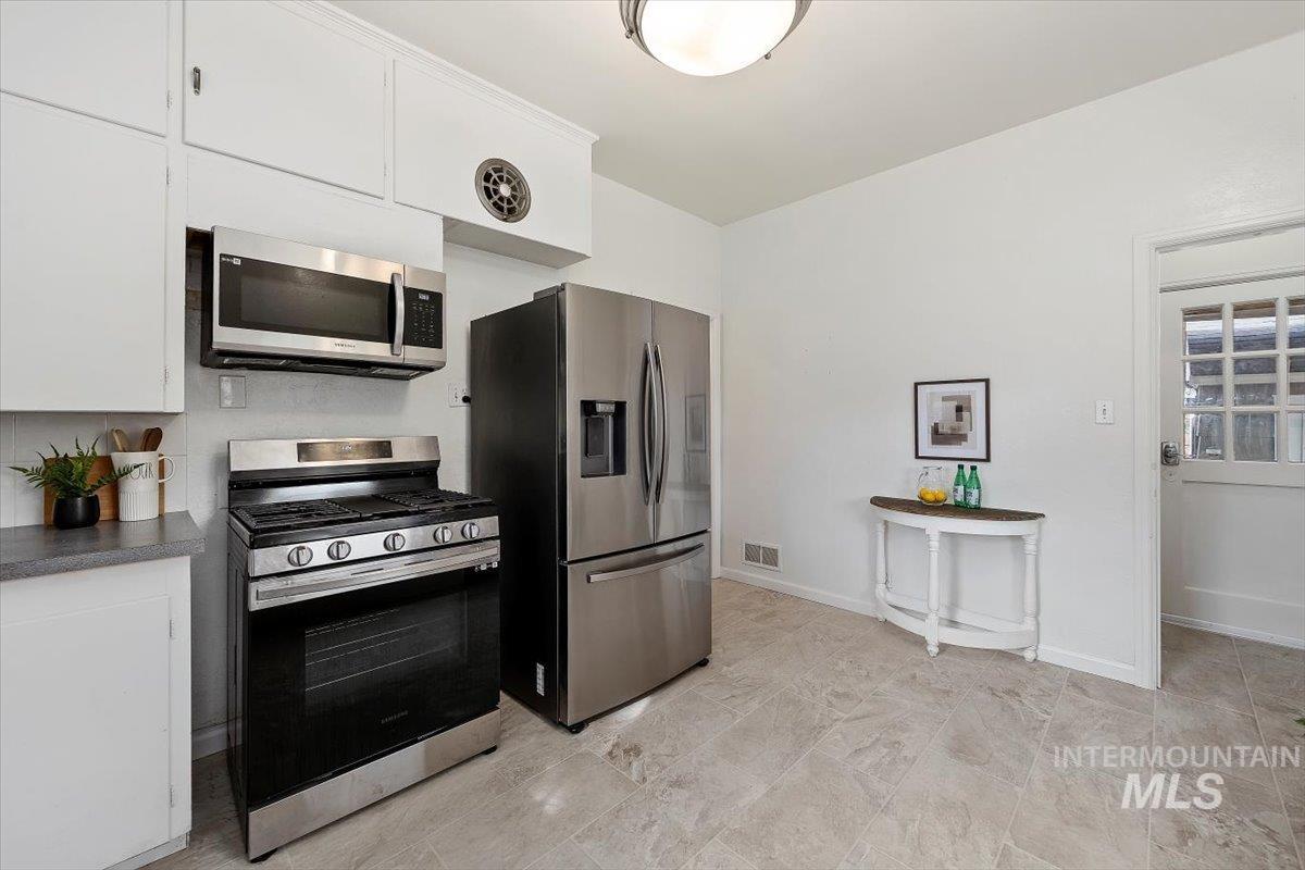 Kitchen with appliances with stainless steel finishes, white cabinetry, and dark countertops
