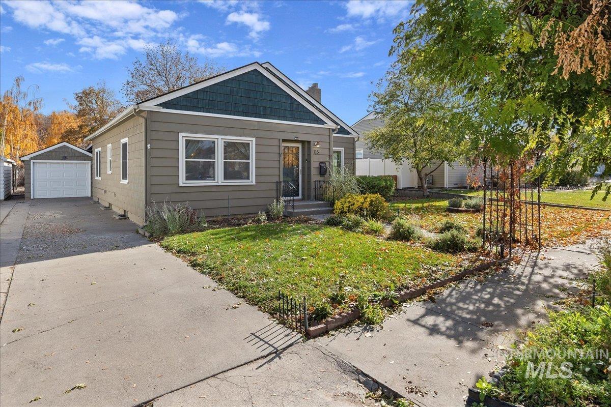 Bungalow featuring a front yard, an outbuilding, concrete driveway, and a chimney