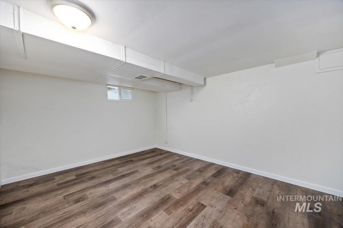 Basement room featuring baseboards and dark wood-style floors
