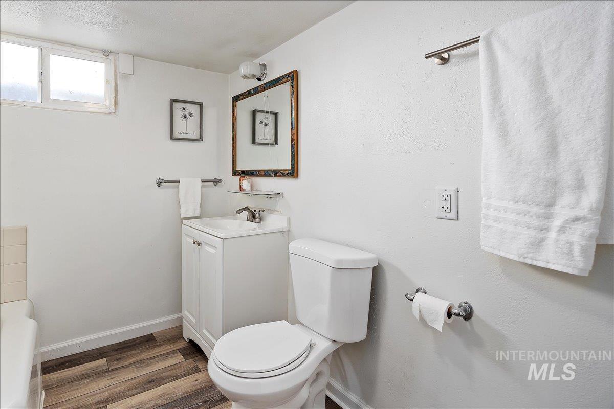 Full bathroom with wood finished floors, vanity, and a tub