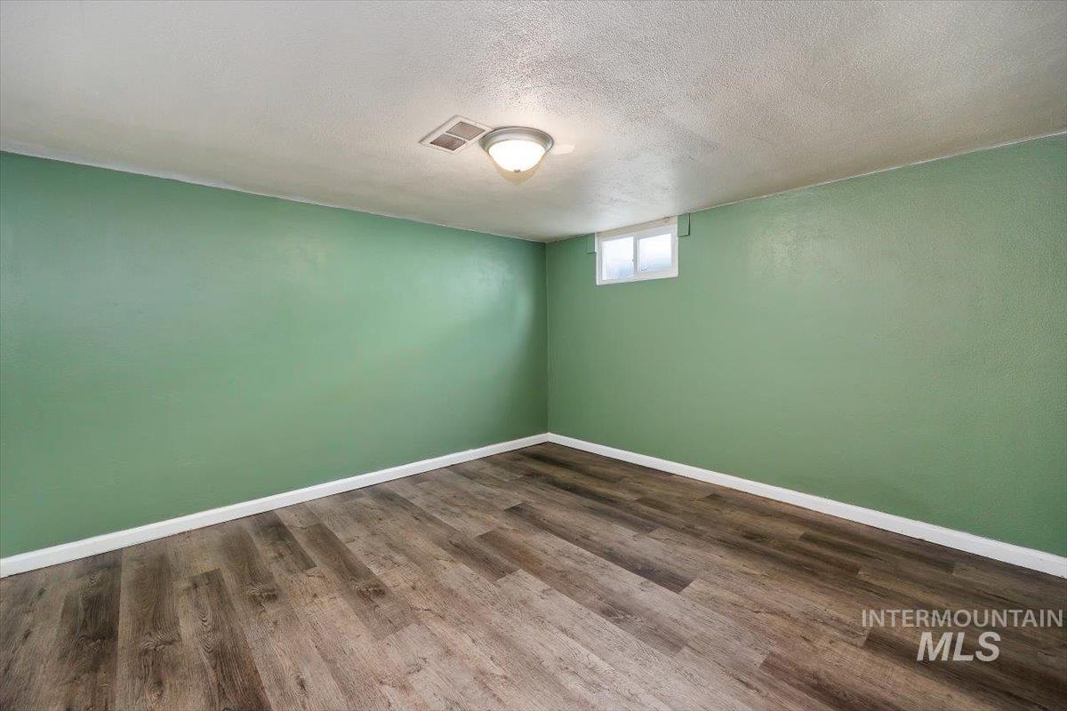 Unfurnished basement room with a textured ceiling and dark wood-style floors