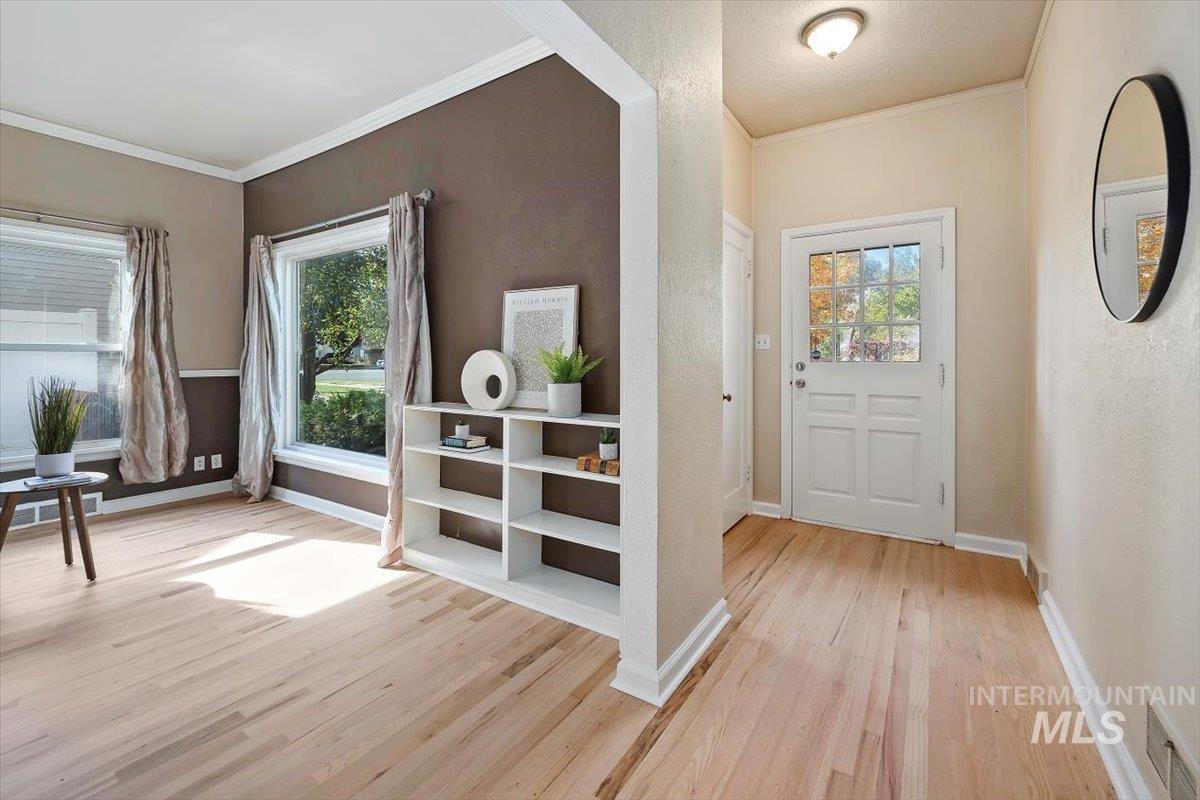 Entryway featuring ornamental molding and light wood-type flooring