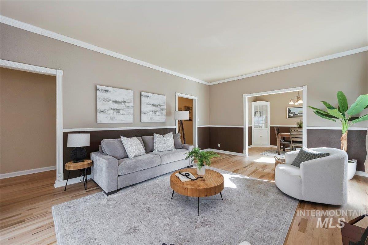 Living area featuring ornamental molding, light wood-type flooring, and a chandelier