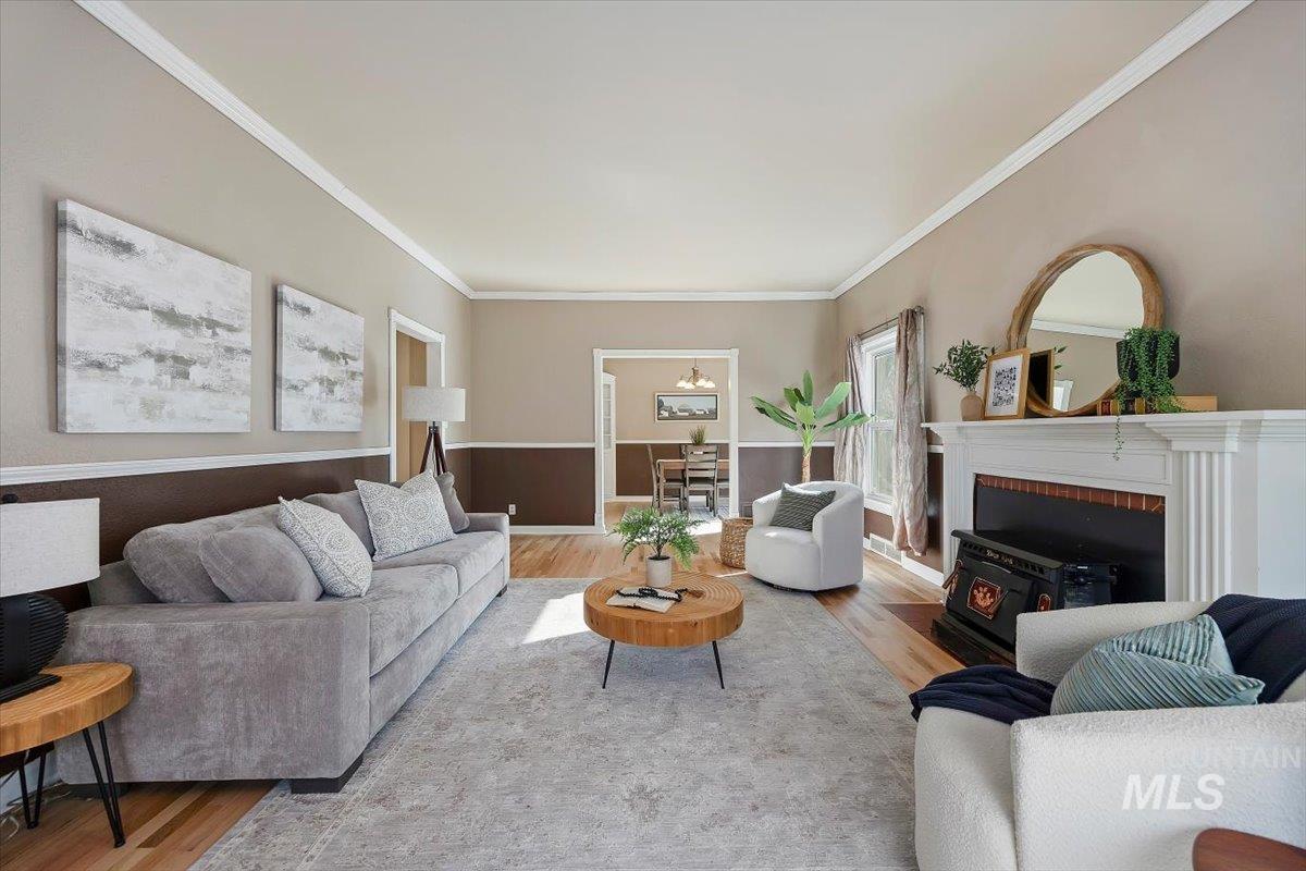 Living area featuring wood finished floors, crown molding, and a wood stove