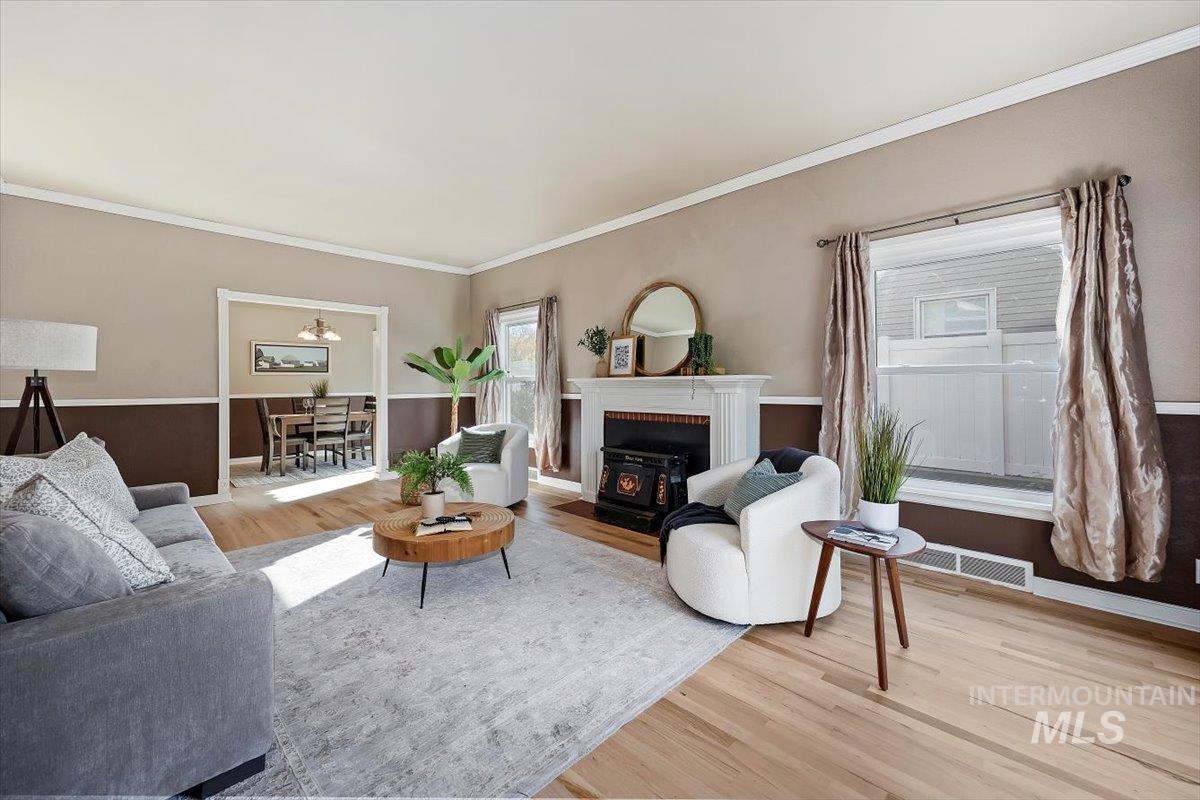 Living area featuring light wood-style flooring, ornamental molding, plenty of natural light, and a brick fireplace