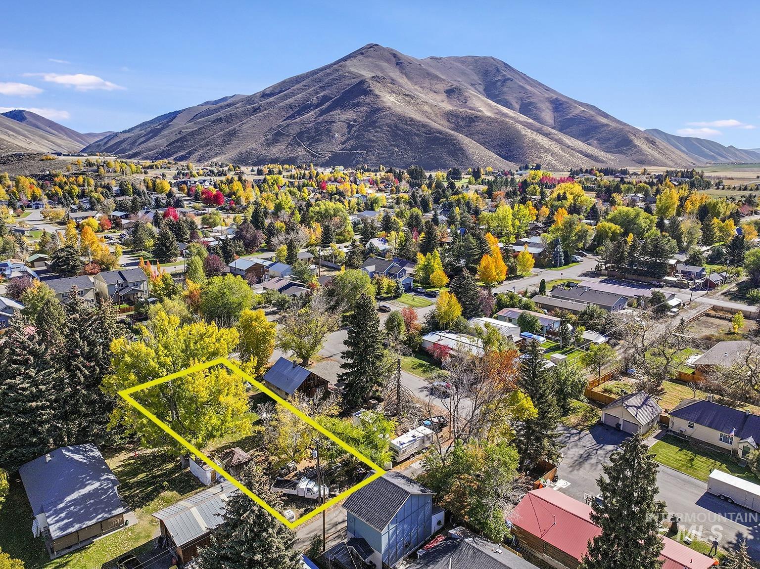 Aerial perspective of suburban area featuring a mountainous background and property boundaries highlighted