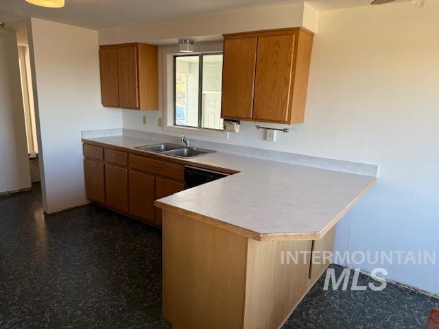 Kitchen with light countertops, a peninsula, brown cabinets, and a kitchen bar