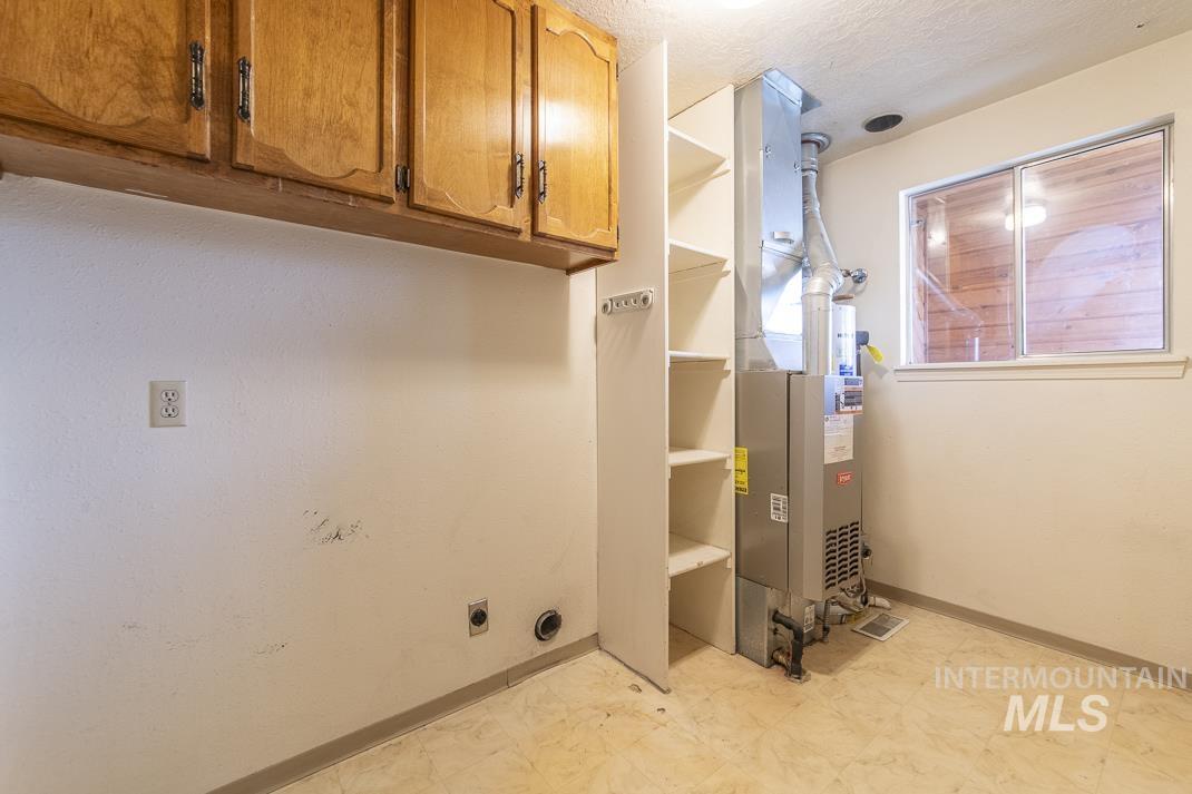 Washroom featuring cabinet space, heating unit, light floors, and a textured ceiling